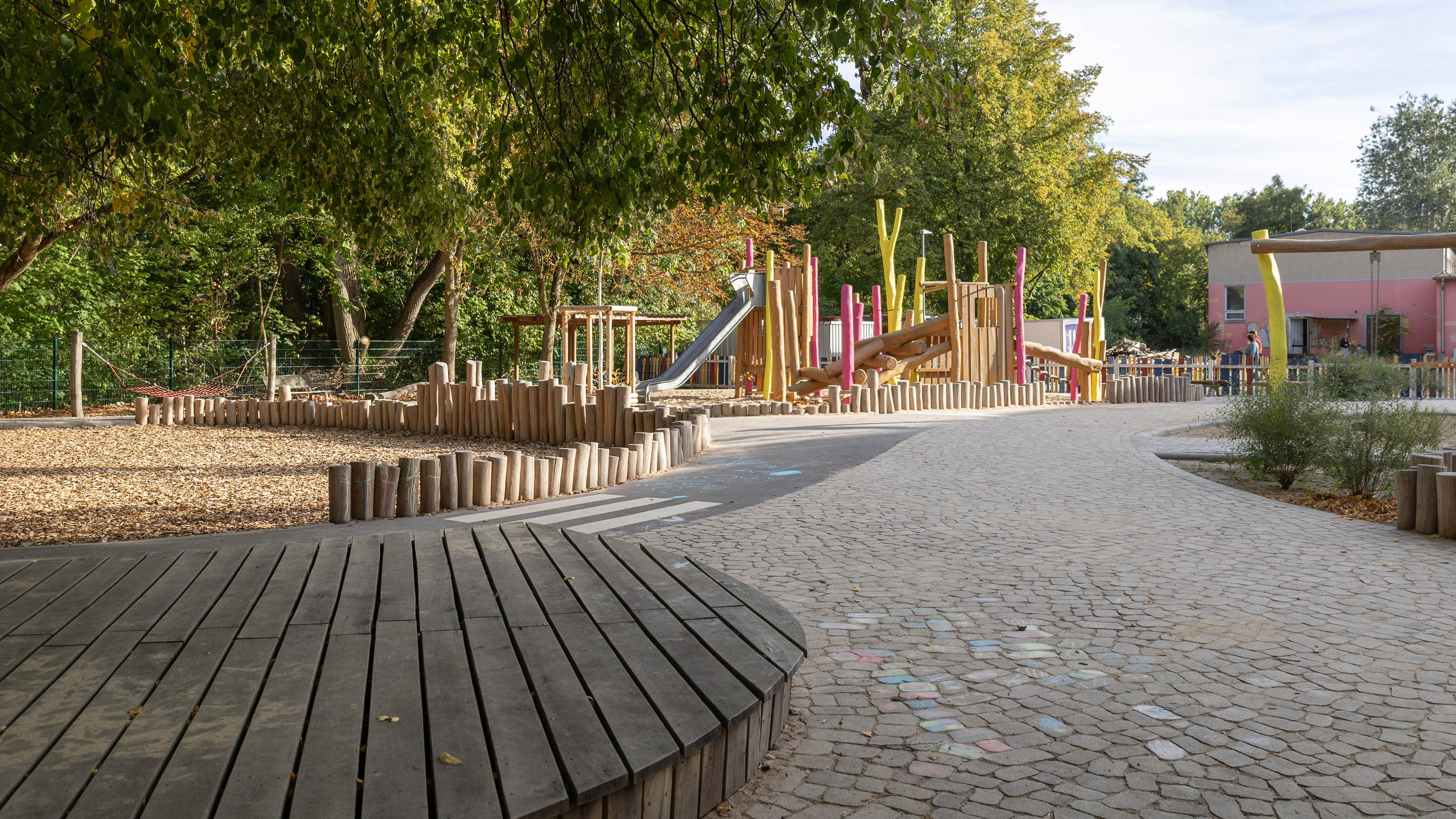 Das großzügige Holzpodest ergänzt die Aufenthaltsbereiche und bietet viel Platz zum Essen, Treffen und Spielen